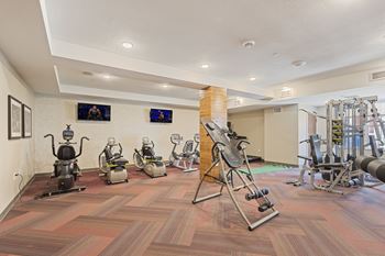 A gym with weights and machines on a wooden floor